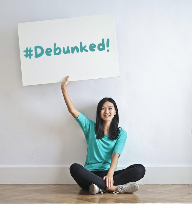 Woman holding a board with the word debunked on it.